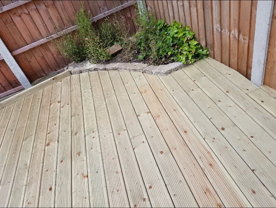 New grooved softwood timber decking laid across an enclosed rear garden