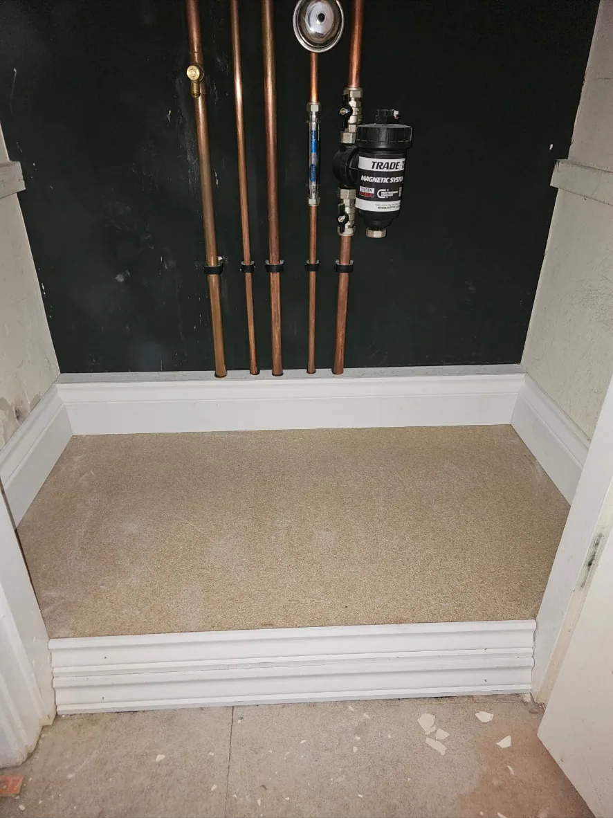 Cupboard housing copper heating pipework, finished with painted walls, new skirting and flooring