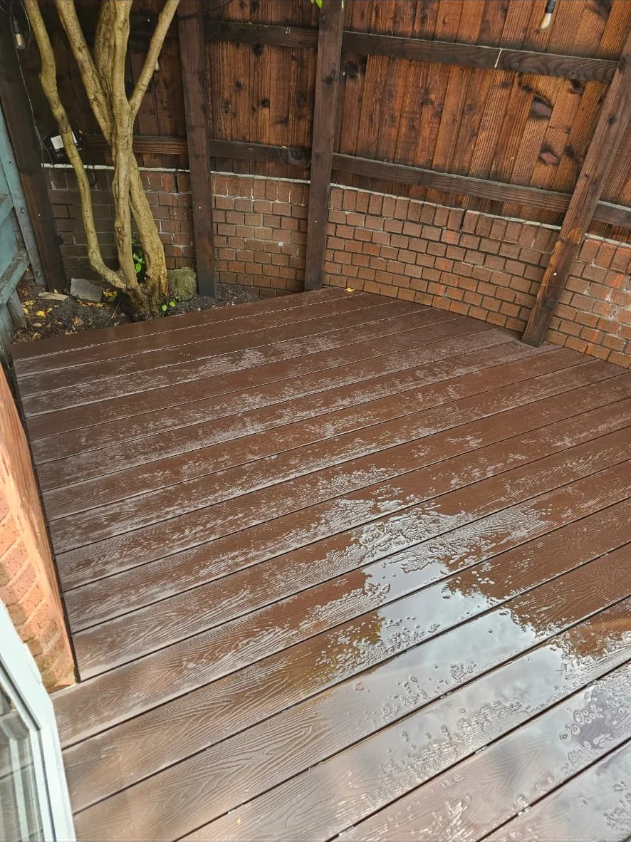 Deck boards laid neatly into the corner between the brick wall and the fence line
