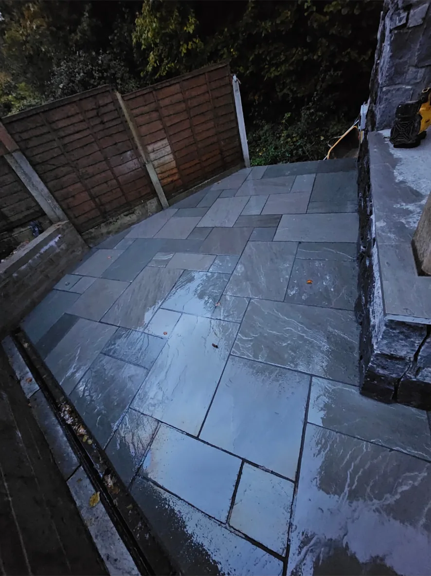 Natural stone paved patio with stone-faced walls in an enclosed rear garden