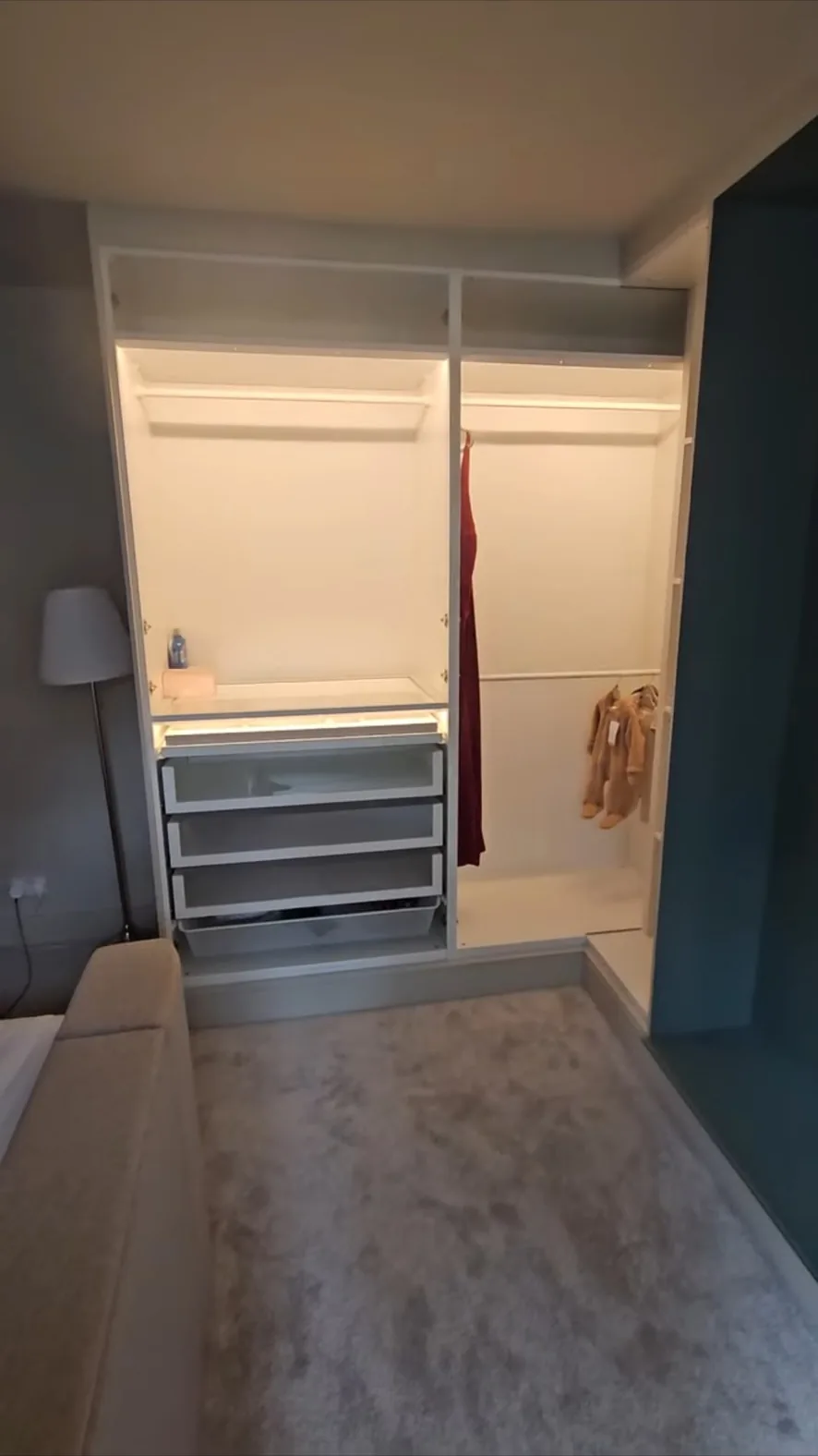 Built-in wardrobe interior with lit shelving, hanging rail and drawer unit in a bedroom