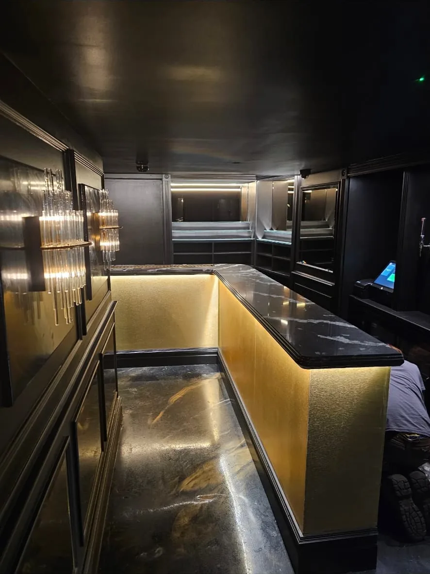 Completed bar with gold panelled front, dark stone counter top and a lit mirrored back bar