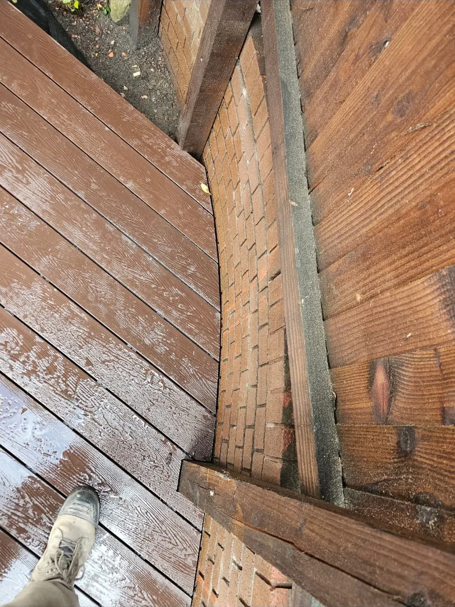 Close view of the deck boards scribed around the curved brickwork and timber posts